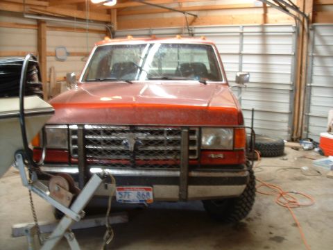 1988 Ford F-150 - Front view of a red Ford truck with a brush guard and winch, parked indoors.