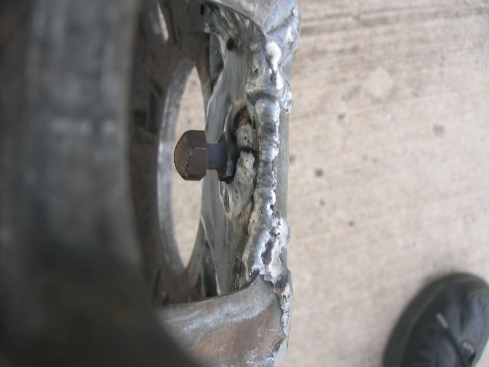 Welded metal part with a bolt, showing rough welds and a circular opening