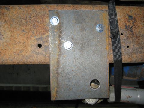 1978 Ford Bronco - A close-up view shows a metal bracket secured with bolts to a heavily rusted vehicle frame.