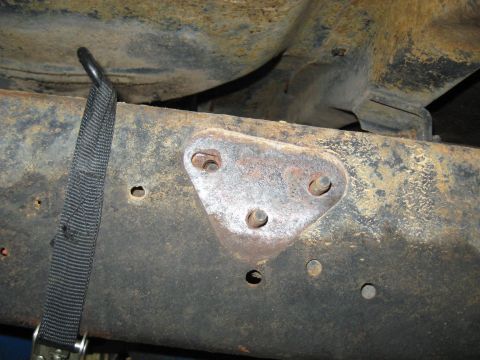 1978 Ford Bronco - Detail of a vehicle's undercarriage, showing a frame section and a securing strap.