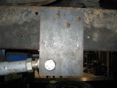 1978 Ford Bronco - Close-up view of a metal bracket attached to a heavily rusted vehicle frame, with a large bolt visible.