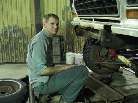 1978 Ford Bronco - A man works on the front end of a vehicle, possibly a Ford Bronco, in a garage setting.