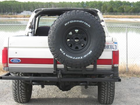 1991 Ford Bronco - Rear view of a white Ford Bronco with a red stripe and a spare tire mounted on the back.