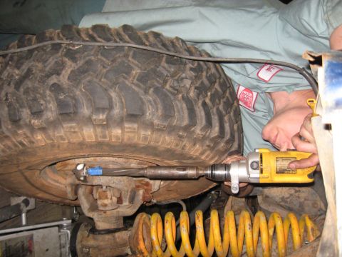 1978 Ford Bronco - Close-up of vehicle suspension repair with a drill and large tire visible.