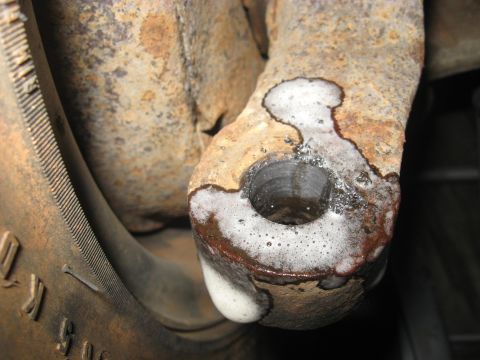 1978 Ford Bronco - A heavily rusted metal part with a hole and foam is shown, with a tire tread visible in the background.