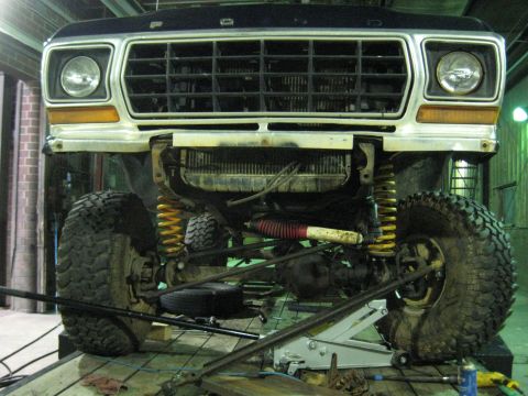 1978 Ford Bronco - Front view of a 1978 Ford Bronco, lifted and undergoing maintenance, showing its suspension and radiator.