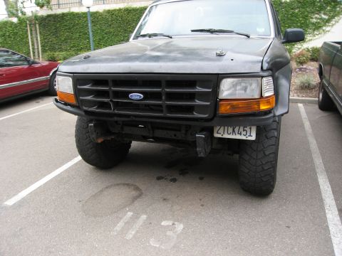 1986 Ford Bronco - This Ford Bronco, likely from the late 1980s, is parked in a lot with a red car to its left.