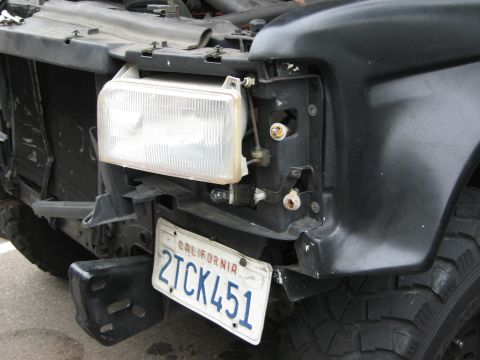 1986 Ford Bronco - The front of a black truck shows significant damage to the headlight area and bumper, with a California license plate attached.