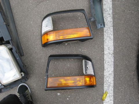 1986 Ford Bronco - Pair of 1986 Ford Bronco headlight assemblies laid out on pavement.