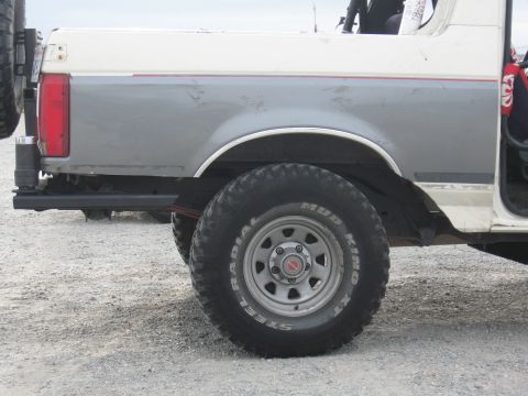 1991 Ford Bronco - The rear of a 1991 Ford Bronco is shown from the side, with a spare tire mounted on the back.