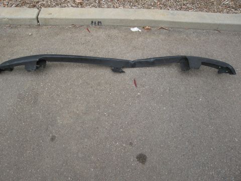 1986 Ford Bronco - A damaged black plastic bumper part lies on the ground.