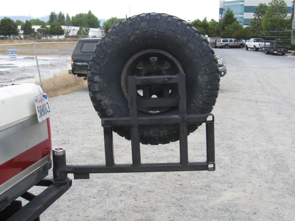 Rear-mounted spare tire carrier on a truck, with a large off-road tire