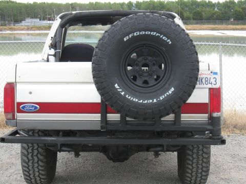 1991 Ford Bronco - Rear view of a white Ford Bronco with a red stripe and a spare tire mounted on the back.