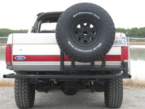 1991 Ford Bronco - Rear view of a white Ford Bronco, a red stripe and a spare tire mounted externally.