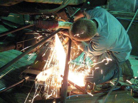1978 Ford Bronco - A mechanic works on the undercarriage of a vehicle, creating a shower of sparks.