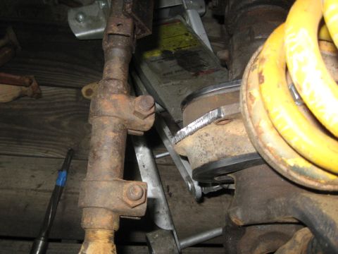 1978 Ford Bronco - Close-up view of suspension components, including a jack and a yellow coil spring, with some visible text on a jack instruction manual.