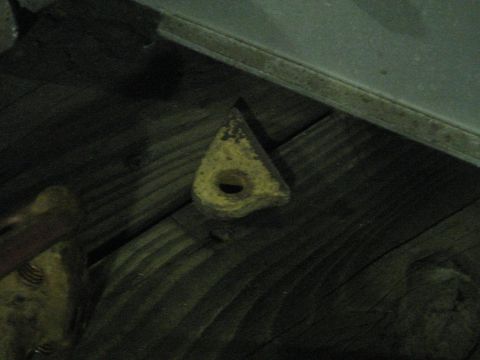 1978 Ford Bronco - A close-up view of a triangular metal object with a central hole, positioned on a surface of wooden planks.