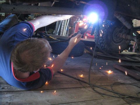1978 Ford Bronco - A person is welding the undercarriage of a vehicle in a workshop setting.