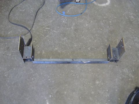 1978 Ford Bronco - A fabricated metal frame part, possibly for a vehicle, lies on a concrete floor.