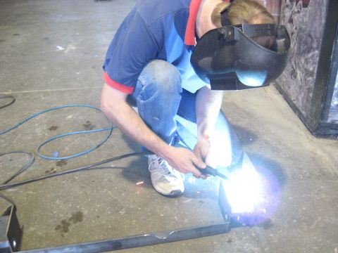 1978 Ford Bronco - A person wearing a welding mask and jeans works on metal with a welding torch, creating bright sparks.