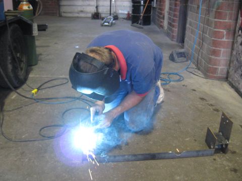 1978 Ford Bronco - Welder working on a metal fabrication project in a garage setting.