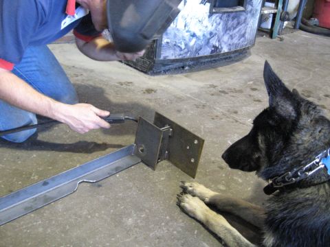 1978 Ford Bronco - A man welds metal components in a workshop while a dog observes the process.