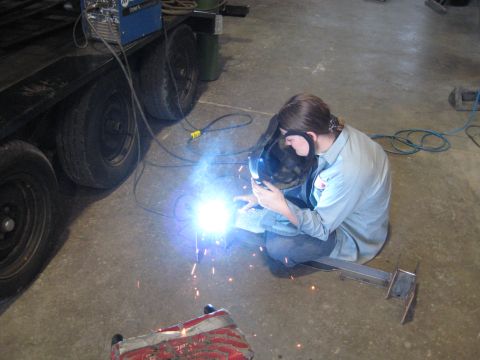 1978 Ford Bronco - Welding a metal frame with sparks flying. A trailer is parked nearby.