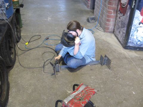 1978 Ford Bronco - A person welds metal components in a workshop environment with welding equipment nearby.