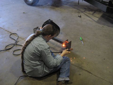 1978 Ford Bronco - A person welds metal in a workshop, with a screwdriver and welding equipment visible.