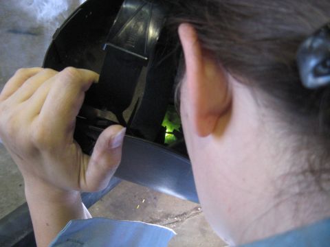 1978 Ford Bronco - A person adjusts the strap on a welding helmet, preparing for work.