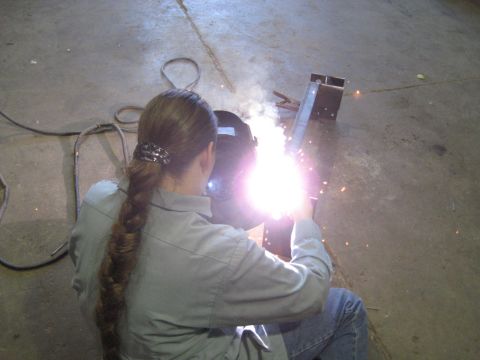 1978 Ford Bronco - A person is welding metal components in an indoor workshop setting.
