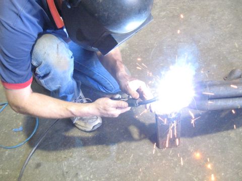 1978 Ford Bronco - A person is welding exhaust pipes in a workshop.