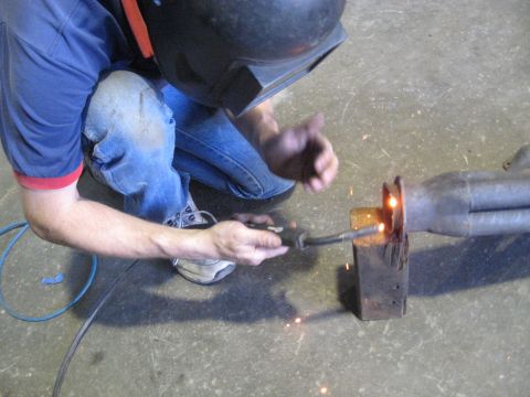 1978 Ford Bronco - A person welds an exhaust pipe, with sparks flying from the joint.