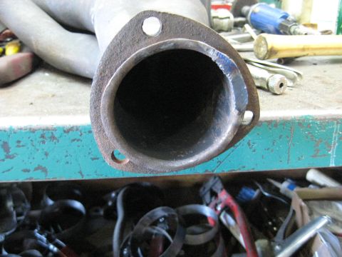 1978 Ford Bronco - A close-up view of a worn exhaust pipe flange, showing signs of modification and rust.