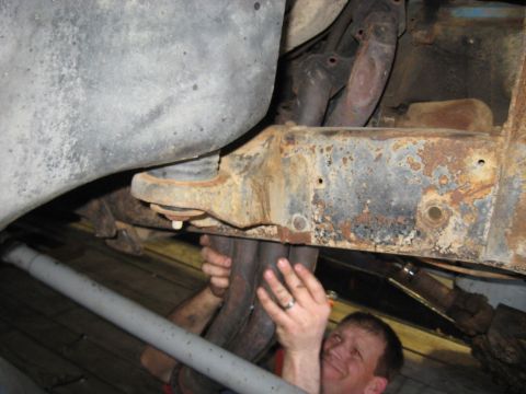 1978 Ford Bronco - Mechanic working on exhaust manifold installation, showing rusty frame components.