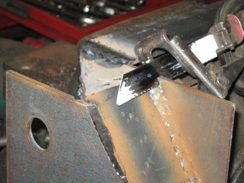 1978 Ford Bronco - A metal bracket is being cut with a hacksaw, showing signs of rust and recent welding.