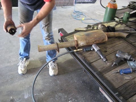 1978 Ford Bronco - Mechanic works on an exhaust pipe with air tools laid out on a trailer bed.