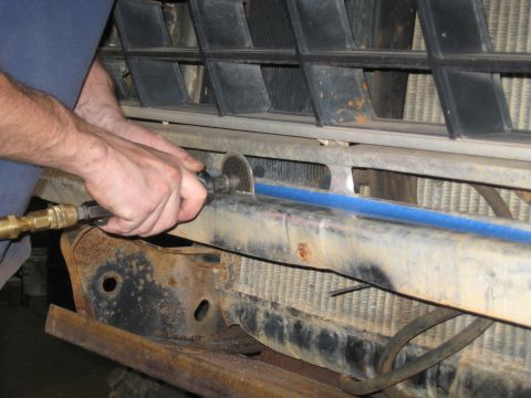 1978 Ford Bronco - A person is cutting a metal bumper on a vehicle, with the grille and radiator in the background.