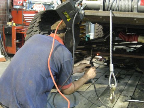 1978 Ford Bronco - Welding repairs being performed on the undercarriage of a vehicle in a workshop.