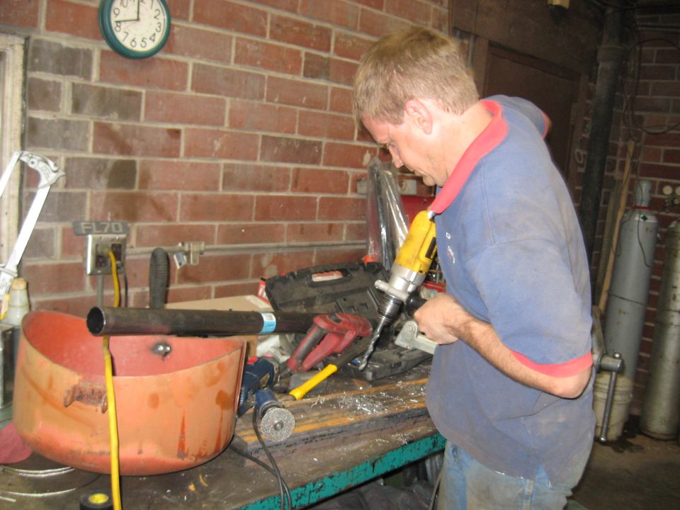 Man drilling metal pipe over orange basin