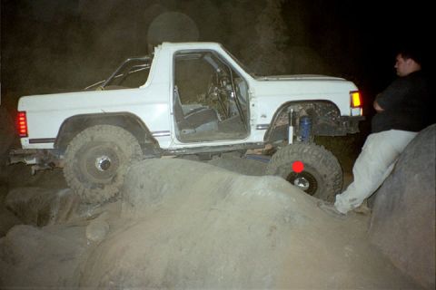 1994 Ford Bronco - A person watches as a modified off-road vehicle navigates a difficult rocky terrain.