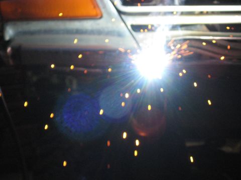 1978 Ford Bronco - A close-up view of welding sparks illuminating the front corner of a vehicle.