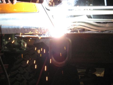 1978 Ford Bronco - Welding is performed on a vehicle's frame, with sparks illuminating the area around the turn signal.