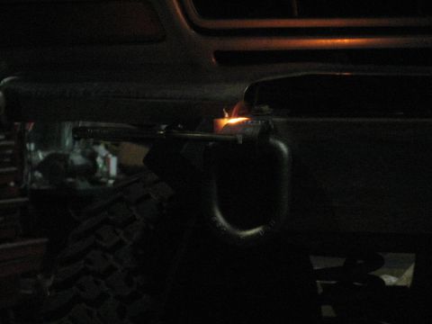 1978 Ford Bronco - Welding a tow hook onto a vehicle bumper in a dark garage.