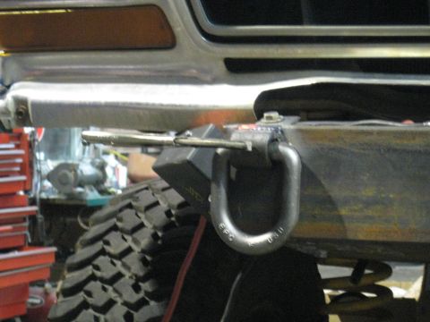1978 Ford Bronco - A tow hook is mounted to the front bumper of a vehicle, with a tire in view.