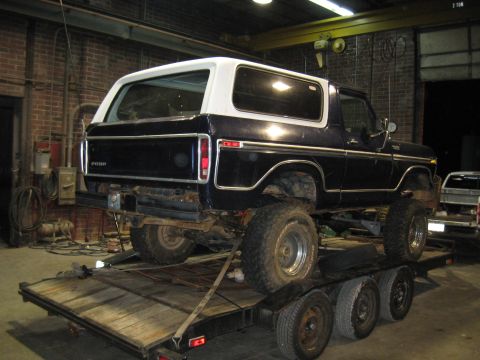 1978 Ford Bronco - A lifted 1978 Ford Bronco is loaded onto a trailer inside a workshop.