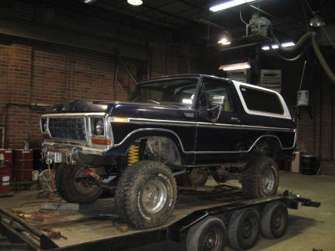 1978 Ford Bronco - 1978 Ford Bronco lifted and on a trailer, likely undergoing modifications in a workshop.