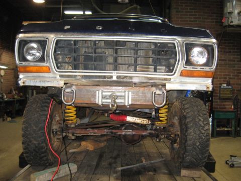 1978 Ford Bronco - Front view of a 1978 Ford Bronco with a winch and custom bumper, showing its lifted suspension and dark blue paint.