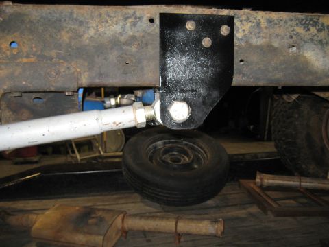 1978 Ford Bronco - Close-up view of a vehicle's undercarriage, showing suspension components, a spare tire, and an exhaust pipe.