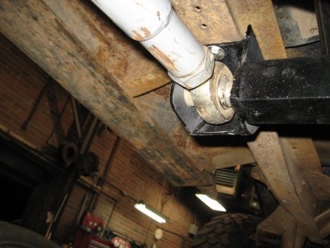 1978 Ford Bronco - Close-up view of the undercarriage of a vehicle, showing rusty frame components and a driveshaft assembly.